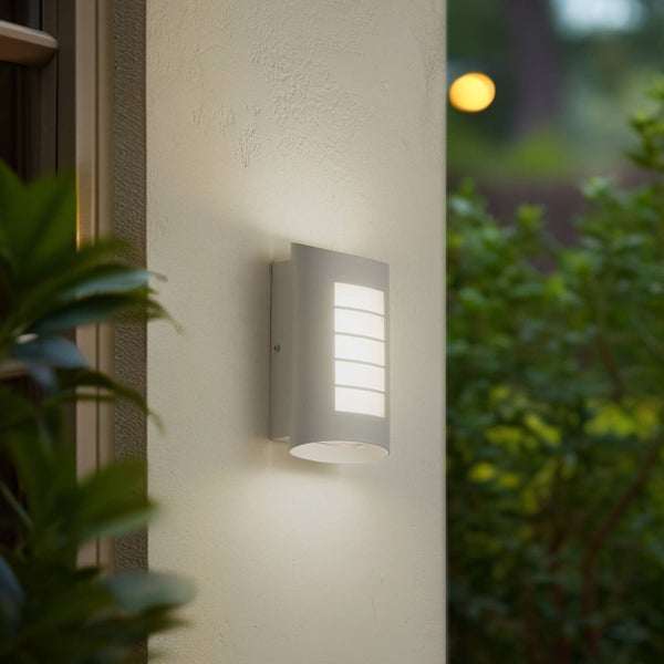 Moderne Außenwandleuchte an einer Hauswand montiert, beleuchtet mit Lichtabstrahlung nach vorne und unten.