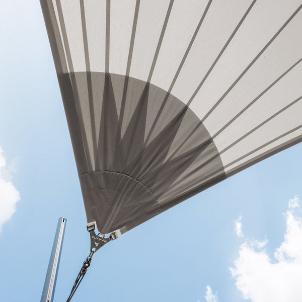 Sonnensegel mit radialer Eckverstärkung und Befestigung an einem Metallmast vor blauem Himmel.