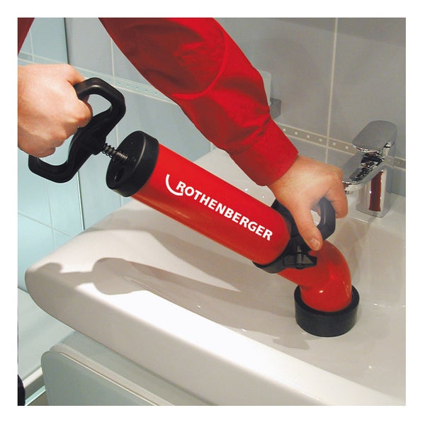 Rote Rothenberger Saug-Druck-Reinigungspumpe zur Rohrreinigung in einem weißen Waschbecken.