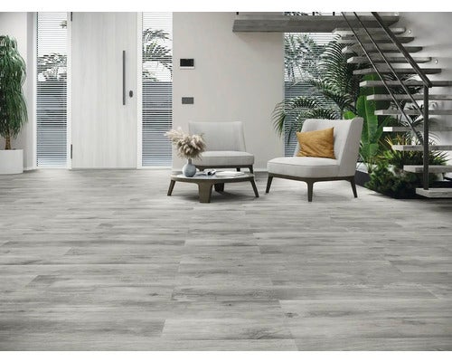 Heller Wohnraum mit grauen Bodenfliesen in Holzoptik, Sesseln und Treppe.