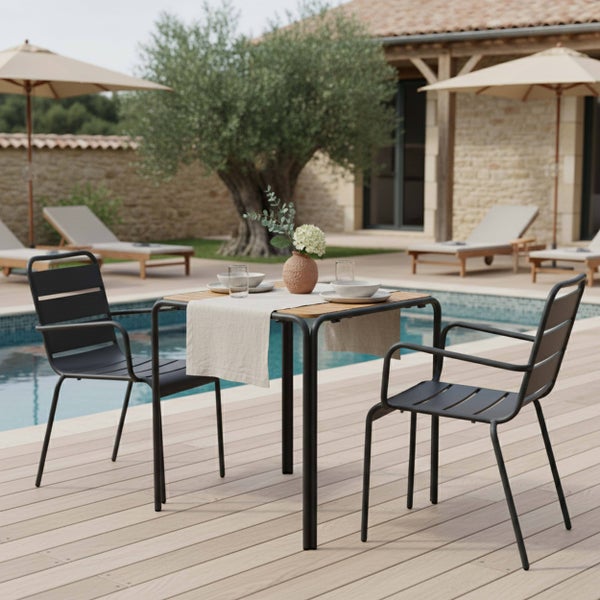 Modernes Gartenmöbel-Set mit quadratischem Holztisch und zwei schwarzen Metallstühlen auf einer Holzterrasse am Pool.