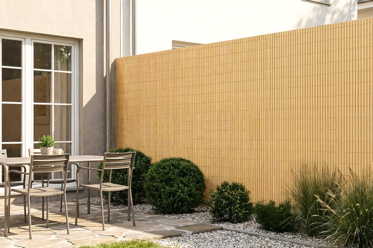 Sichtschutzmatte aus Bambus als natürlicher Garten Sichtschutz auf einer Terrasse mit Sitzgruppe und Pflanzkübeln.