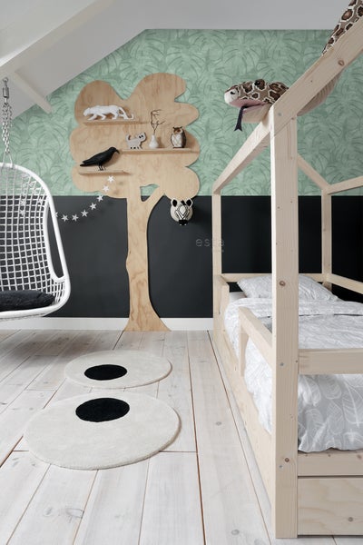 Kinderzimmer mit Holzbett, Hängesessel, Baumregal und runden Teppichen