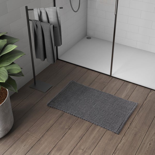 Graue Badematte vor einer Dusche mit Handtuchhalter
