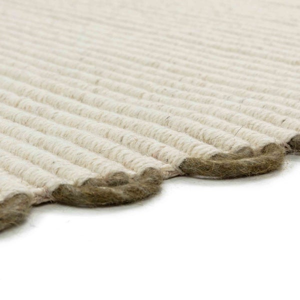 Nahaufnahme eines gewebten Teppichs mit Rippenstruktur und Schlaufenrand aus Naturfasern.