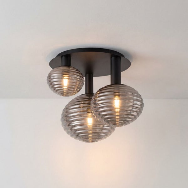 Dreiflammige Deckenleuchte mit schwarzer runder Basis und drei unterschiedlich großen, geriffelten Glasschirmen.