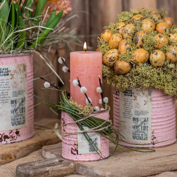 Dekorative Szene mit Kerze, Osterdekoration und Blumen in verzierten Dosen