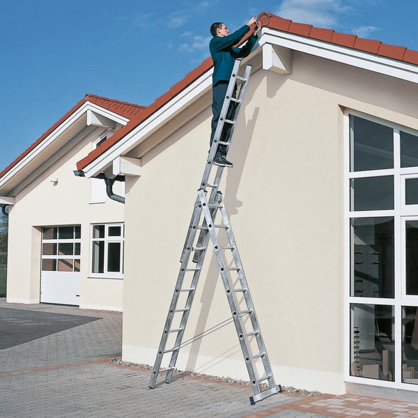 Mann auf einer Mehrzweckleiter bei Dacharbeiten an einem Haus.