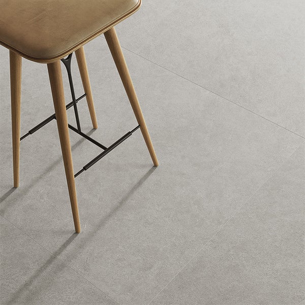 Moderne Bodenfliesen mit Betonoptik in einem minimalistisch gestalteten Raum mit einem Barhocker aus Holz.