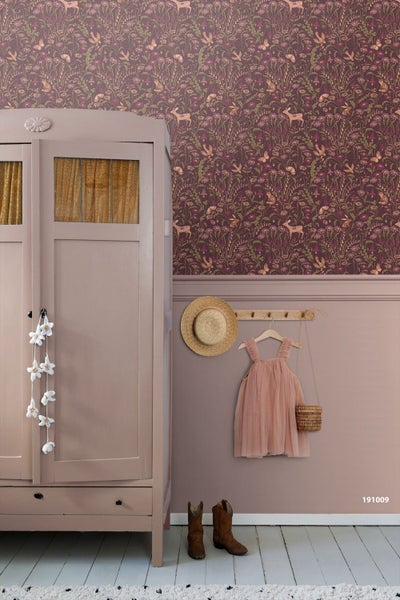Kinderzimmer mit Vliestapete mit Tier- und Blumenmotiven, einem Gitterbett aus Holz und einem Kind, das nach einem Mobile greift.