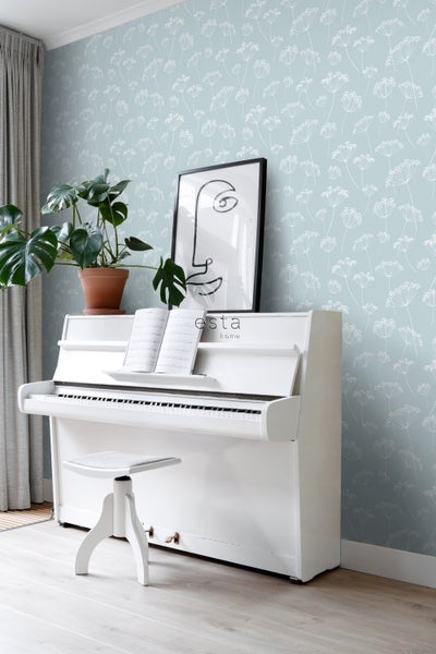 Wohnraum mit weißem Klavier, Hocker, Zimmerpflanze, Kunstdruck und Tapete mit Blütenmuster
