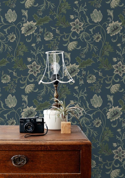 Dekoratives Zimmer mit floraler Tapete, Lampe und Vintage-Kamera auf einem Holztisch