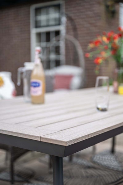 Moderner Gartentisch mit einer Tischplatte in Holzoptik und einem dunklen Metallgestell im Außenbereich.
