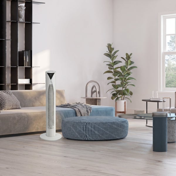 Turmventilator in einem hellen, modern eingerichteten Wohnzimmer mit Sofa, Hocker und Zimmerpflanze.