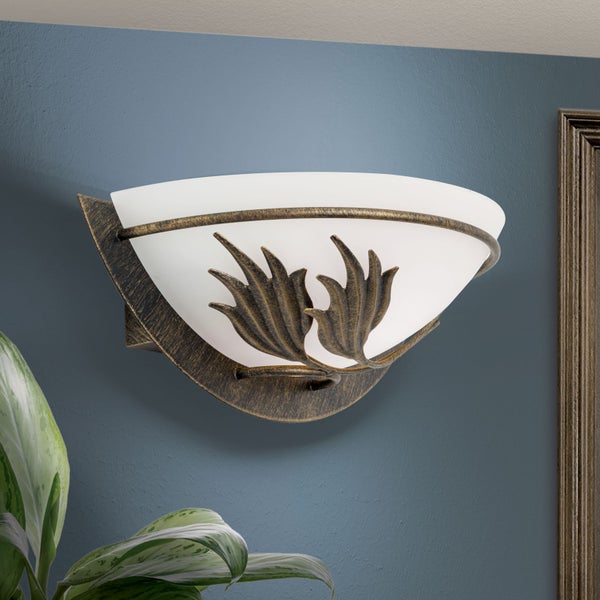 Wandleuchte im Landhausstil aus Metall in Antikoptik mit einem halbrunden Glasschirm und Blattdekoration.