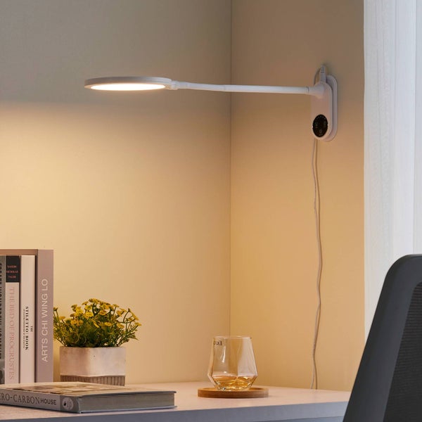 Wandmontierte weiße LED-Schreibtischlampe mit flexiblem Arm, beleuchtet einen organisierten Schreibtisch mit Büchern und einer Pflanze.
