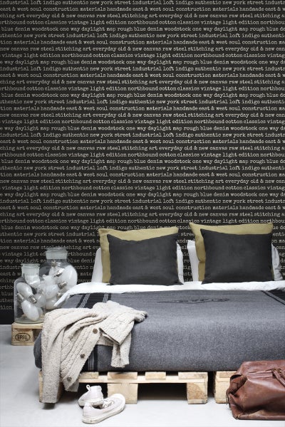 Schlafzimmer mit Palettenbett, grauer Bettwäsche, Kissen und Dekoration