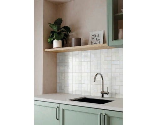 Moderne Küche mit hellgrünem Unterschrank, schwarzem Spülbecken, verchromter Armatur und weißem Fliesenspiegel unter einem Holzregal.