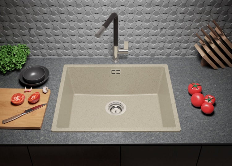 Küchenspüle aus Quarzkomposit mit Armatur, Schneidebrett, Messern und Tomaten auf einer Arbeitsplatte.