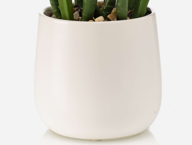 Künstliche Orchidee in einem grauen glänzenden Keramiktopf mit passendem Untersetzer und Dekokies.