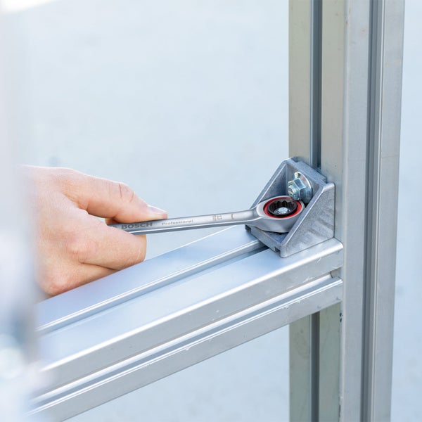 Eine Person benutzt einen Bosch-Ratschenschlüssel an einem Winkelverbinder aus Metallprofilen.