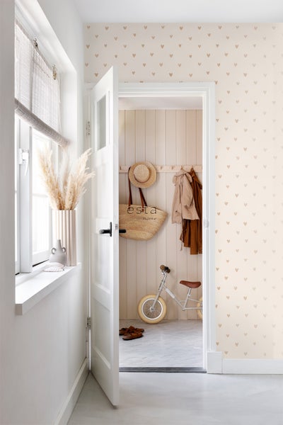 Heller Flur mit Herzchenmuster-Tapete, geöffneter Tür und dekorativen Elementen