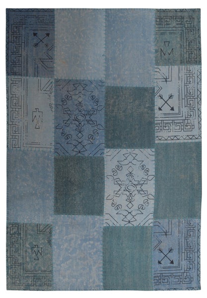 Teppich in Patchwork-Optik mit verschiedenen Blau-Tönen und ethnischen Mustern wie Pfeilen und geometrischen Bordüren.