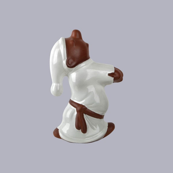 Dekorative Keramikfigur eines Wichtels in Nachthemd und Nachtmütze in liegender Pose.