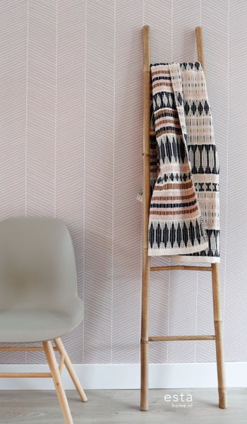 Zimmer mit Stuhl, Leiter und dekorativer Textilie vor einer Tapete mit Pfeilmuster.