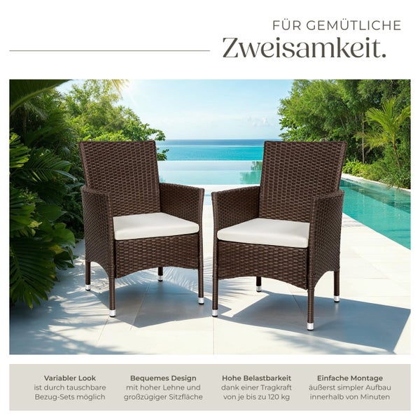 Zwei Rattansessel mit Armlehnen und weißen Sitzkissen auf einer Terrasse