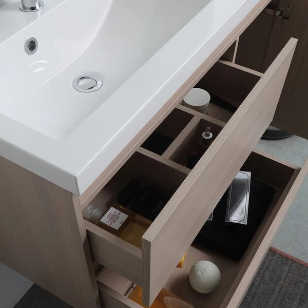 Badezimmer-Waschtischunterschrank in heller Holzoptik mit weißem Waschbecken und geöffneten Schubladen inklusive Inneneinteilung.