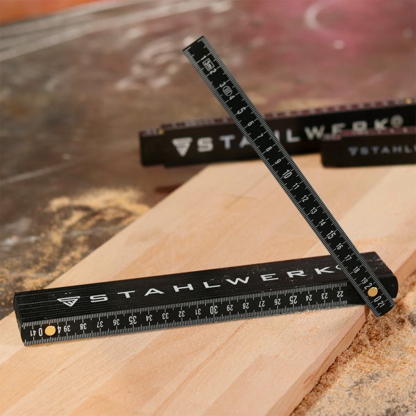 Gliedermaßstab von Stahlwerk auf einem Holzbrett in einer Werkstatt.