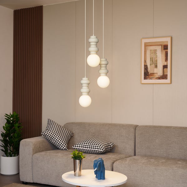 Szene eines Wohnzimmers mit einer modernen dreiflammigen Pendelleuchte über einem Sofa