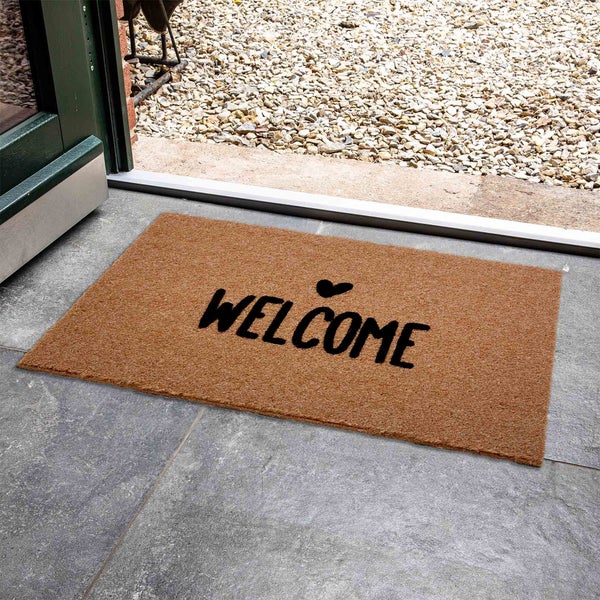 Fußmatte mit Willkommensaufdruck vor einer Haustür