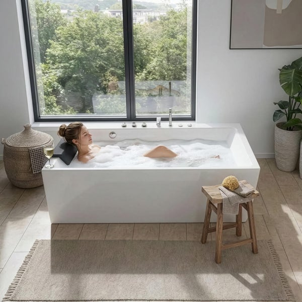 Frau entspannt in einer modernen, freistehenden Badewanne in einem hellen Badezimmer mit großem Fenster, Holzhocker und Dekoration.