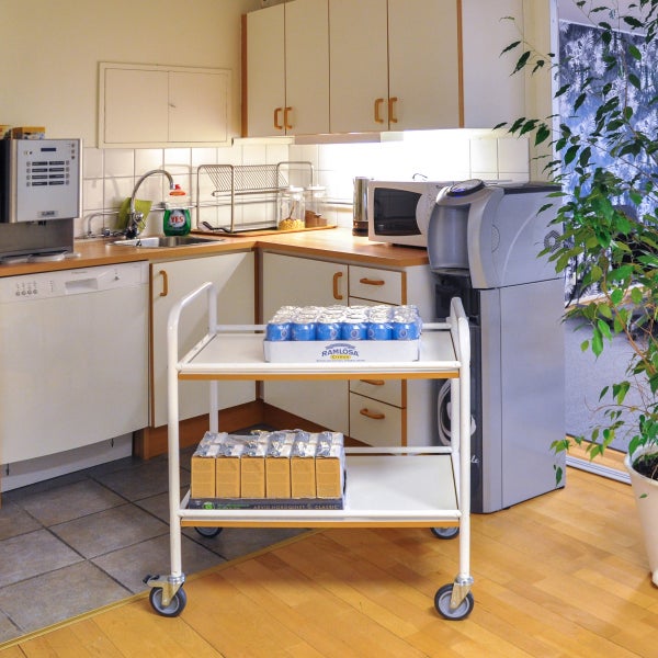 Küchenszene mit Servierwagen, Getränken und Küchengeräten in einem hellen Raum.