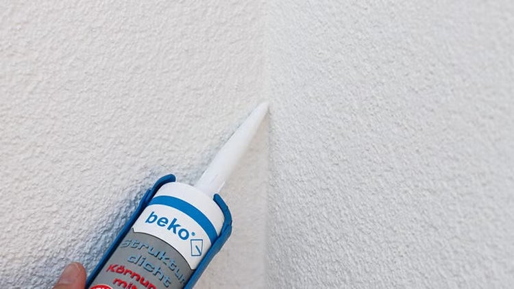 Anwendung von beko Strukturdicht mit einer Kartuschendüse in eine Ecke einer Wand mit Strukturputz.