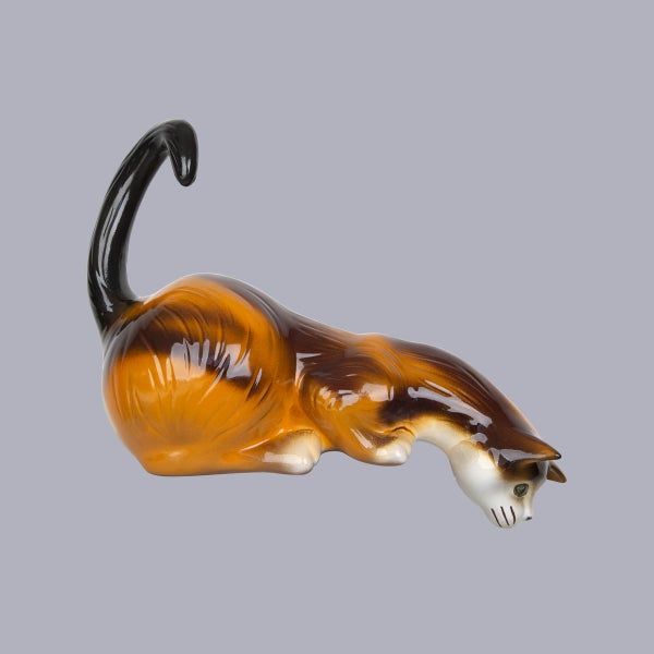 Katzenfigur aus Keramik in Braun und Orange, liegend mit aufrechtem Schwanz.
