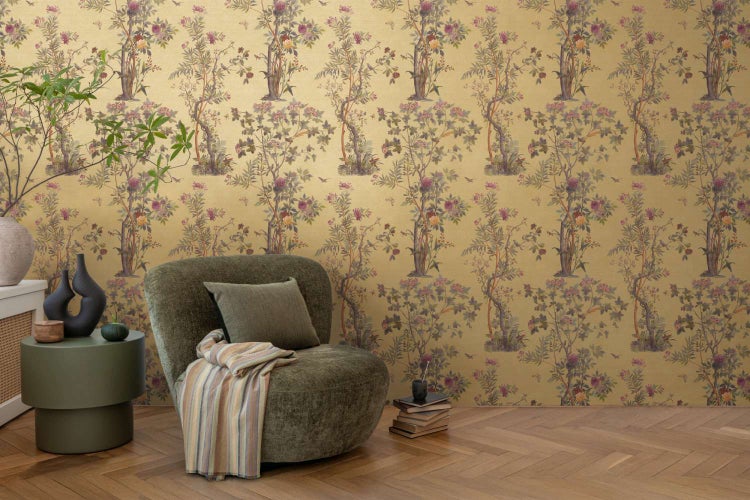 Vliestapete mit floralem Chinoiserie Muster in einem Wohnraum mit Sessel und Beistelltisch auf Parkettboden.