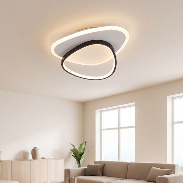 Moderne organisch geformte LED-Deckenleuchte in einem hellen Wohnzimmer über einem Sofa und Sideboard.