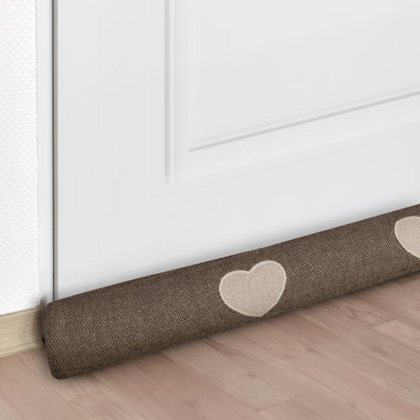 Zugluftstopper mit Herzmuster vor einer Tür