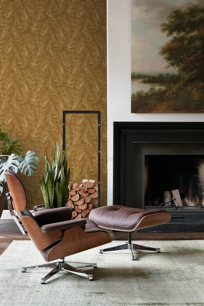 Wohnzimmer mit Sessel, Ottomane, Kamin, Holzstapel und Blättertapete
