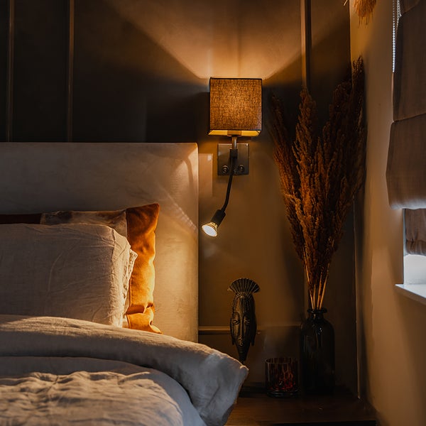 Schlafzimmer mit Bett, Nachttisch und Wandleuchte mit Leselampe