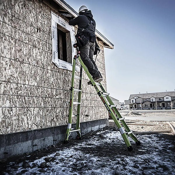 Bauarbeiter auf einer Teleskop-Mehrzweckleiter aus Glasfaser an einer Holzwand auf einer Hausbaustelle.