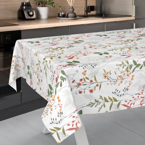 Rechteckige Tischdecke mit floralem Blätter- und Blütenmuster auf einem weißen Tisch in einer modernen, hellen Küche.