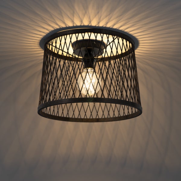 Deckenleuchte mit einem Lampenschirm aus Drahtgeflecht und einer brennenden Glühbirne, die ein Strahlenmuster an die Decke wirft.