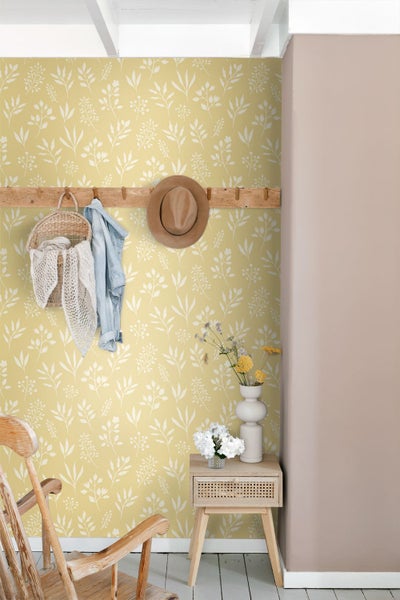 Helle Flurgestaltung mit Vliestapete mit botanischem Muster, Holzgarderobe und Nachttisch in einem organisierten Raum.