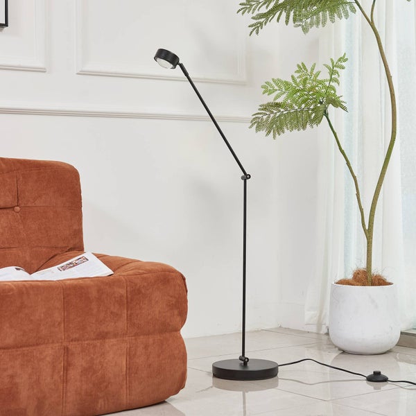 Schwarze Stehlampe neben einem Sessel und einer Zimmerpflanze