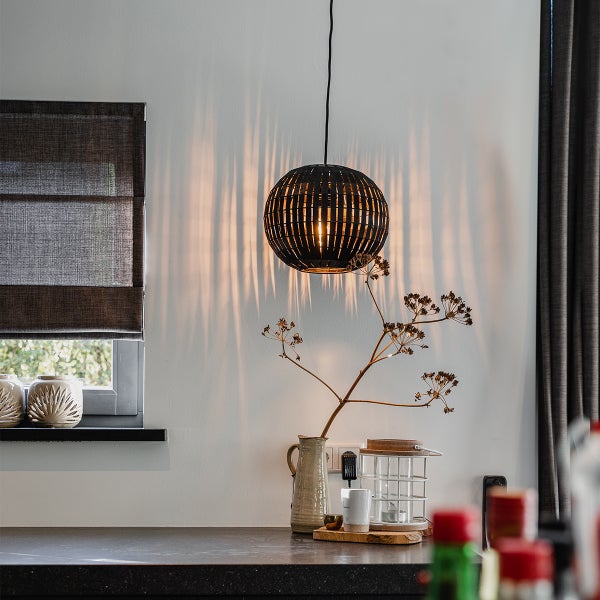 Szene mit einer runden Hängelampe, die Lichteffekte an die Wand wirft, kombiniert mit dekorativen Elementen in einem Raum.