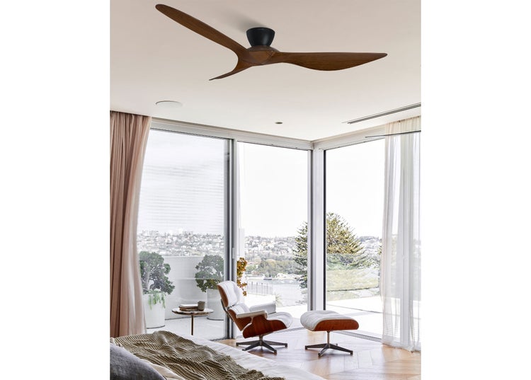 Moderner Deckenventilator mit drei Holzflügeln in einem hellen, offen gestalteten Wohnbereich mit Loungesessel und Blick auf die Stadt.